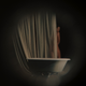 A woman behind a curtain stands in front of a bathtub in the game Immortality.